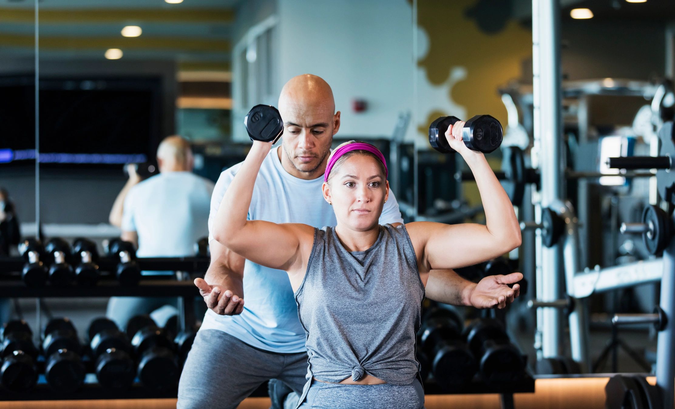 Personal trainer coaching a woman lifting dumbbells