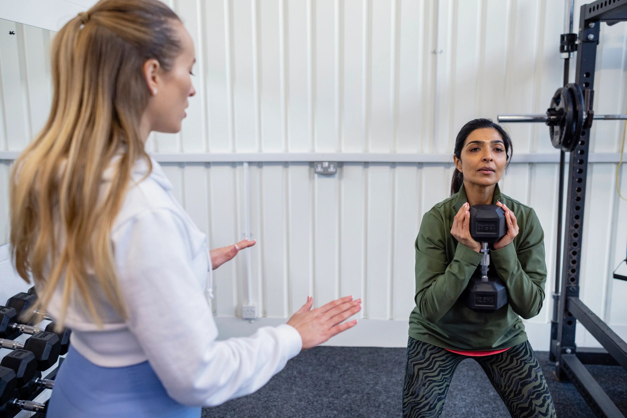 Trainer coaching a client during weighted squats