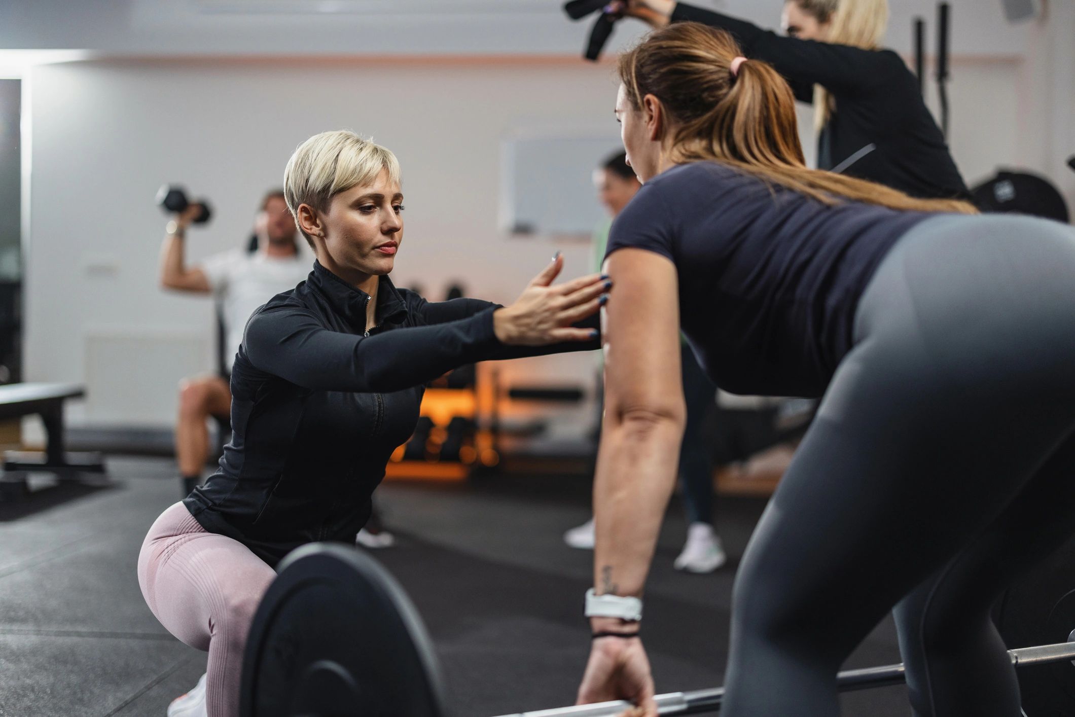 Trainer coaching a client during a deadlift in the gym