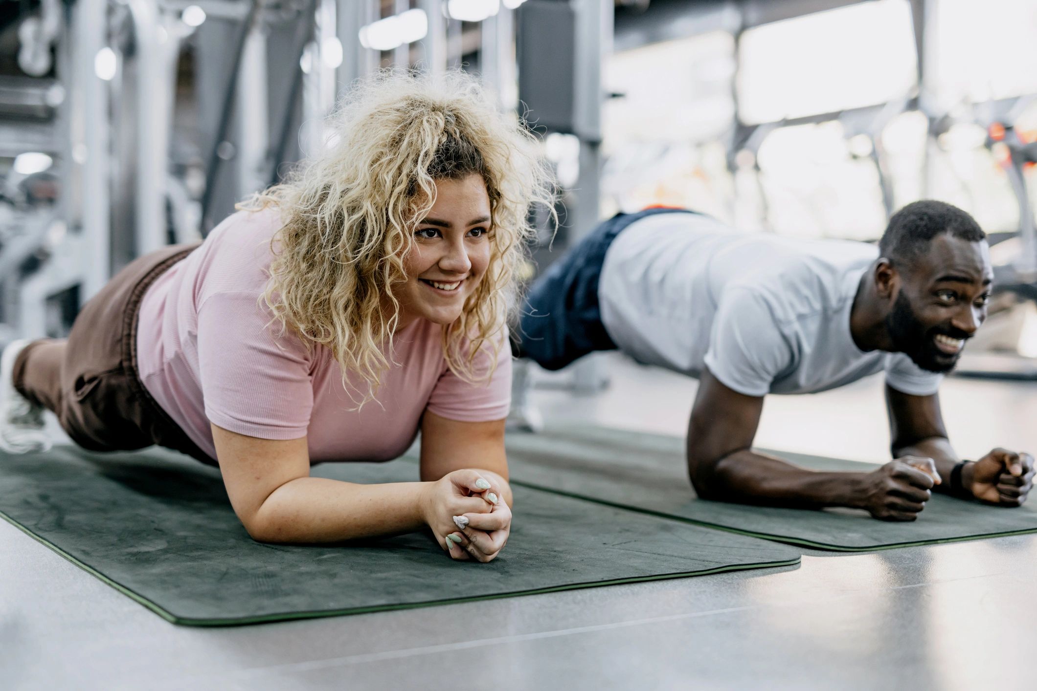 Two gym partners smiling during a plank workout