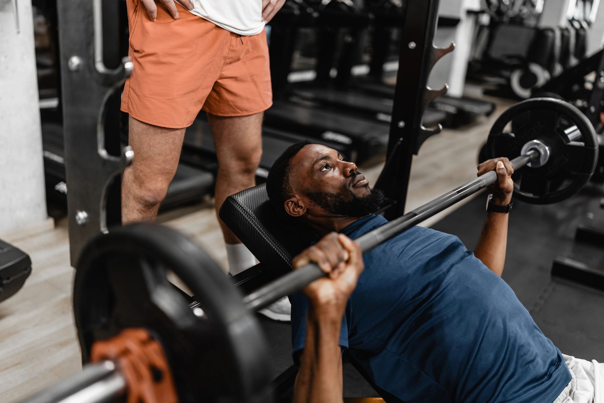 Athlete bench pressing with a spotter in a gym